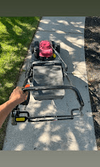 Commercial push mower on a sidewalk beside a freshly cut lawn