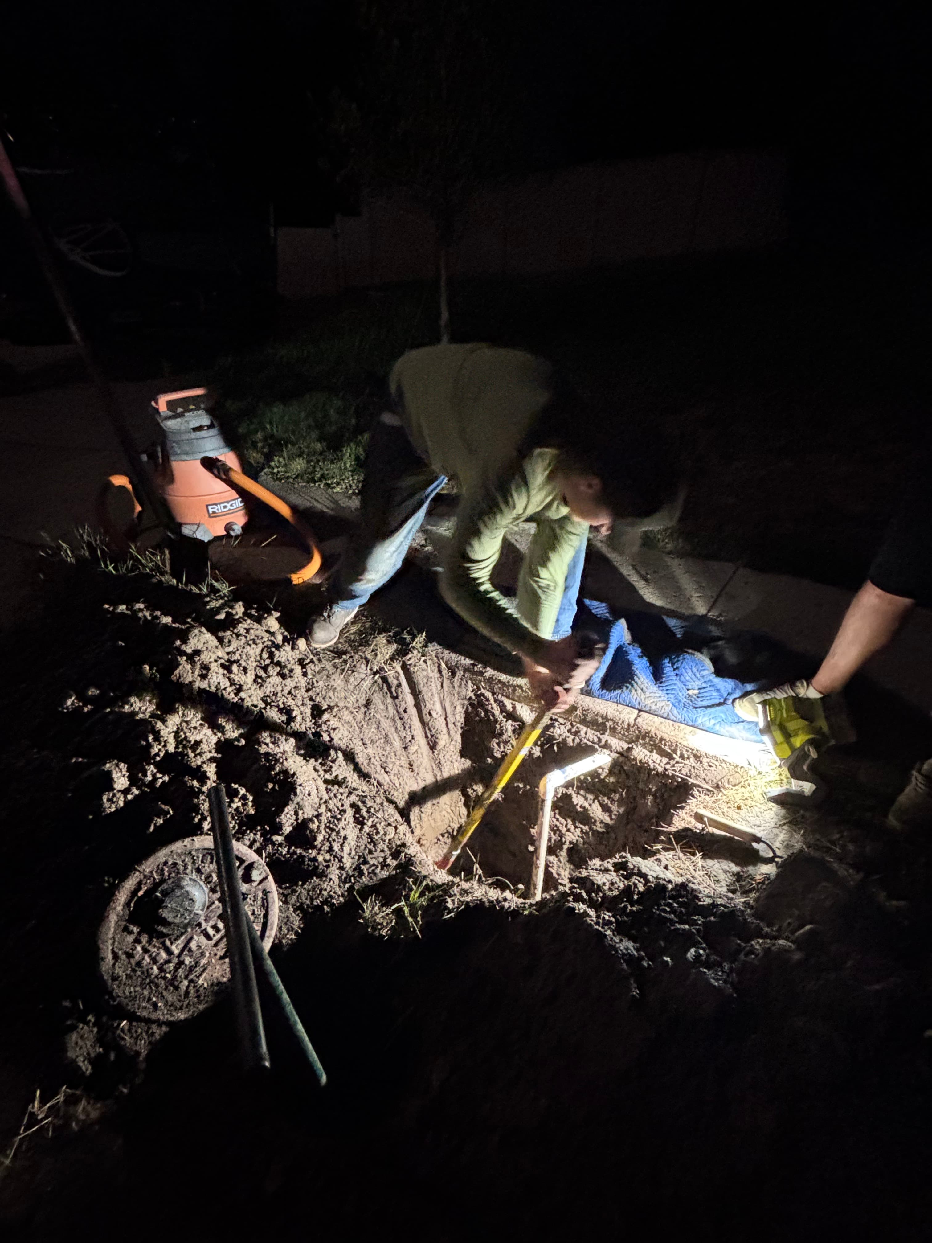 Everwork crew digging out a broken sprinkler line at night