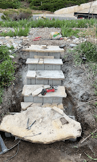 Stone steps being set into a hillside with tools on the landing